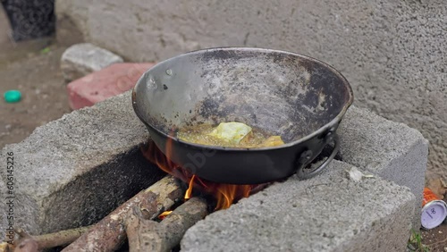 Closeup of frying the fish pieces in the pan on the brick stove in traditional style photo