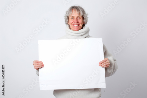 Senior woman holding a blank white sheet of paper on a white background