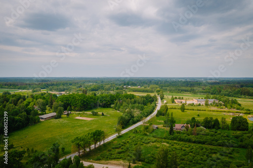 Aerial view of a road that leads past fields and forests in sunny weather