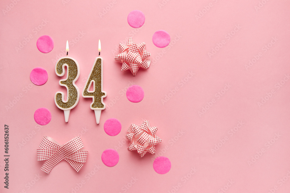 Number 34 on pastel pink background with festive decor. Happy birthday candles. The concept of celebrating a birthday, anniversary, important date, holiday. Copy space. Banner