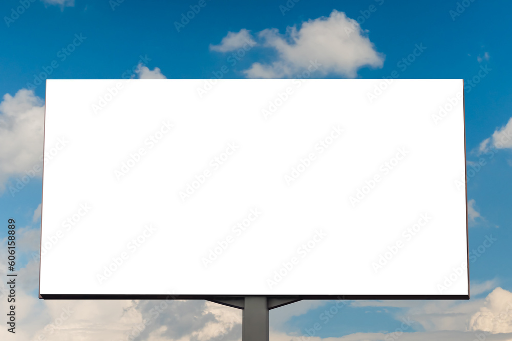 Fototapeta premium Mock up - blank horizontal white billboard or large advertising display against blue sky with white clouds. Mock up, consumerism, white screen, template and copy space concept