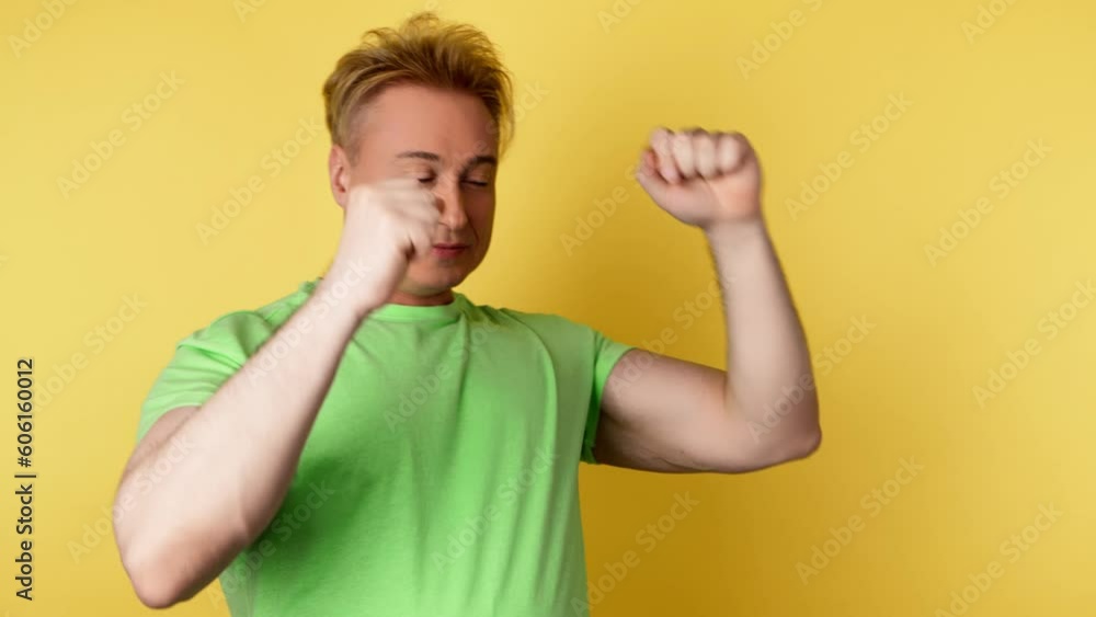 Positive man dancing having fun rhythm to music, enjoying life, entertainment. Carefree guy excited dance in a yellow sweatshirt. Studio shot isolated on yellow background. Positive man dancing having fun rhythm to music, enjoying life, entertainment. Carefree guy excited dance in a yellow sweatshirt. Studio shot isolated on yellow background.