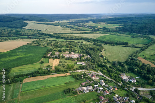 Aerial landscape view of green cultivated agricultural fields with growing crops and distant village houses