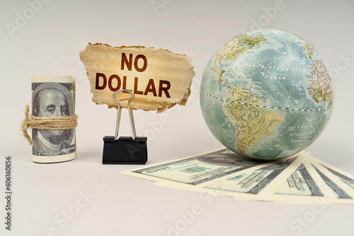 On the table are dollars, a globe and there is a sign with the inscription - no dollar photo