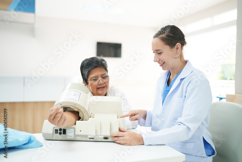 Female doctor doctor measuring senior female s blood pressure at medical clinic.