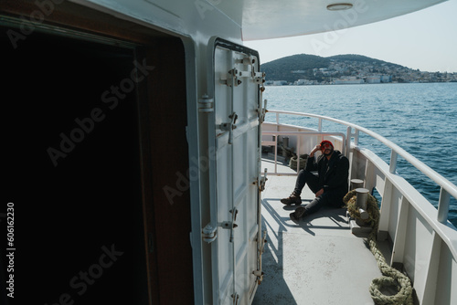 the figure of a young man sitting on board a moving ferry. marine background