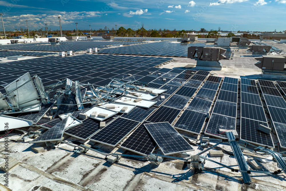 Top view of destroyed by hurricane Ian photovoltaic solar panels mounted on industrial building roof for producing green ecological electricity. Consequences of natural disaster in Florida - obrazy, fototapety, plakaty 
