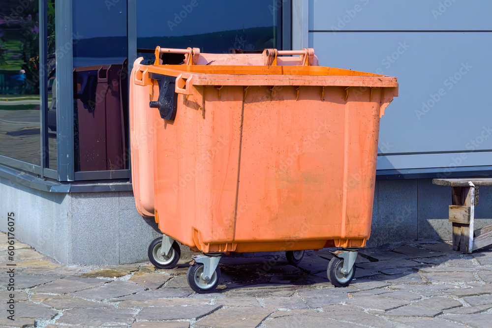 Orange plastic trash recycling container.Orange container for collecting garbage. Orange plastic trash recycling container.Orange container for collecting garbage.