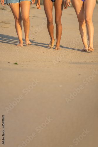 Legs of friends walking in the sand