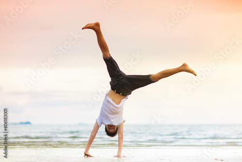 Fotografie Teenager doing calisthenics exercise. Beach yoga.