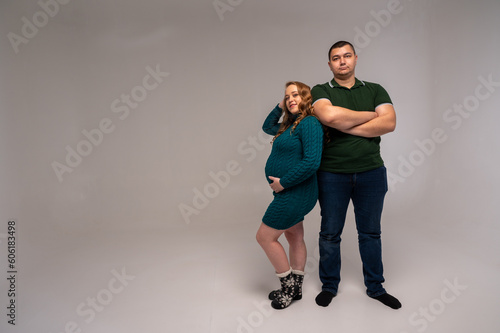 Image of happy young man standing with his pregnant wife isolated on white wall background. Growing a family, expecting a child, a young family, emotions