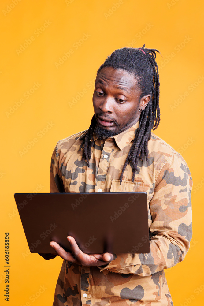 Thoughtful young adult searching for marketing ideas, checking business strategy using laptop computer in studio. Pensive african american holding digital gadget, browsing on internet Thoughtful young adult searching for marketing ideas, checking business strategy using laptop computer in studio. Pensive african american holding digital gadget, browsing on internet
