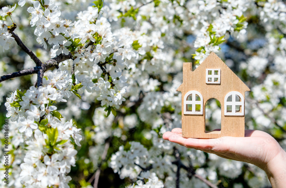 The girl holds the house symbol against the background of blossoming cherry
The girl holds the house symbol against the background of blossoming cherry