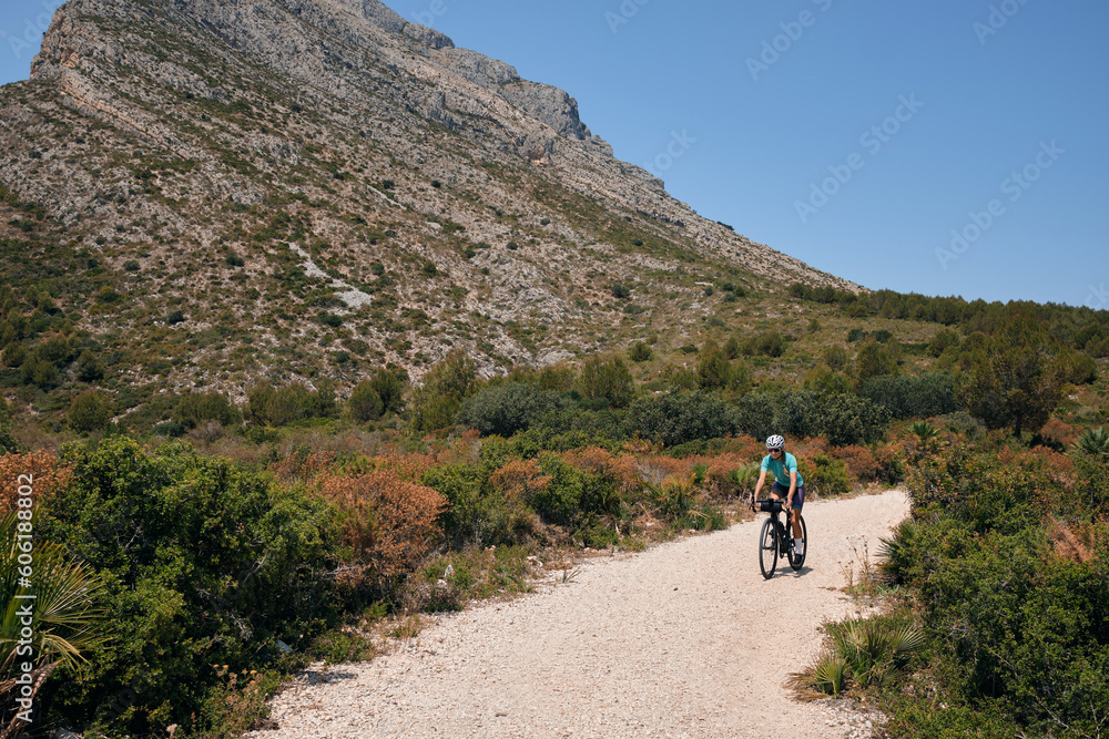 Fit female cyclist riding dirt trails on a gravel bike.Gravel road in mountains.Alicante region of Spain.