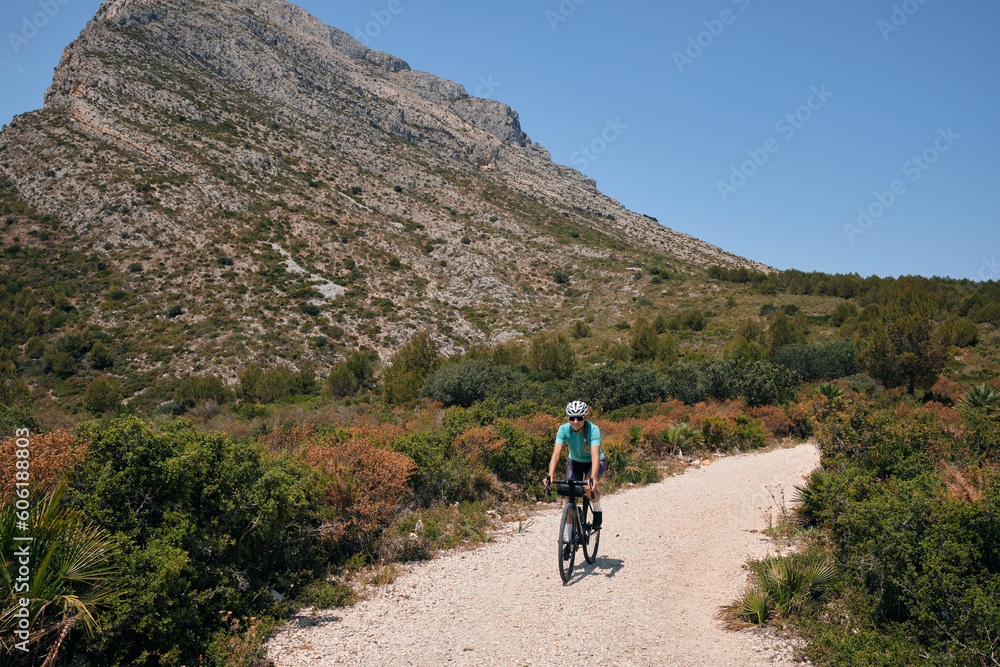 Fit female cyclist riding dirt trails on a gravel bike.Gravel road in mountains.Alicante region of Spain.