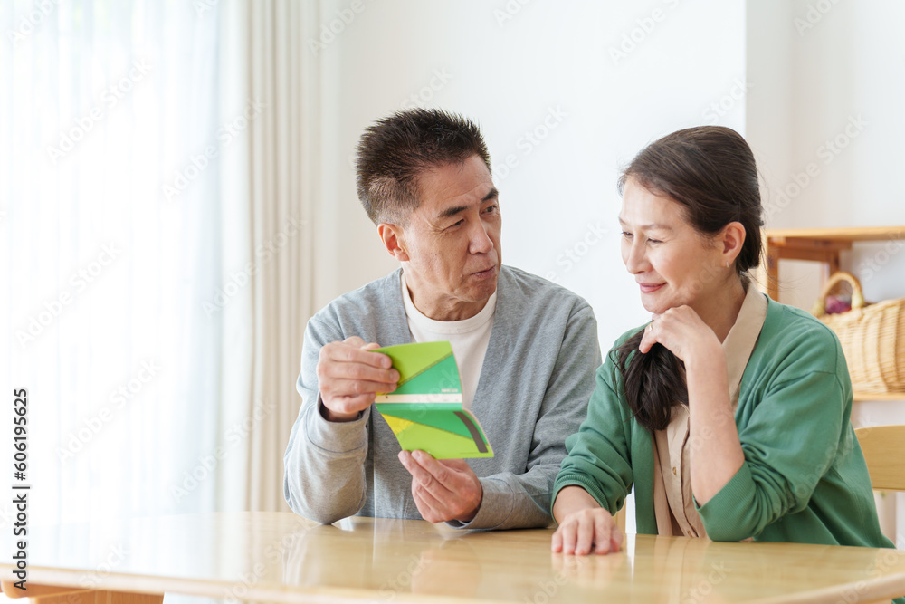 通帳を見て悩むシニア夫婦 通帳を見て悩むシニア夫婦