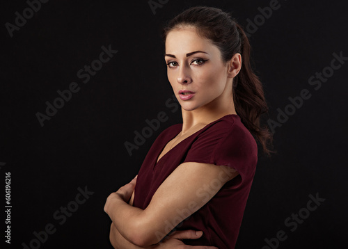 Beautiful serious makeup woman with long brown healthy wavy hair style in casual clothing in red blouse.  Closeup portrait on studio black background.