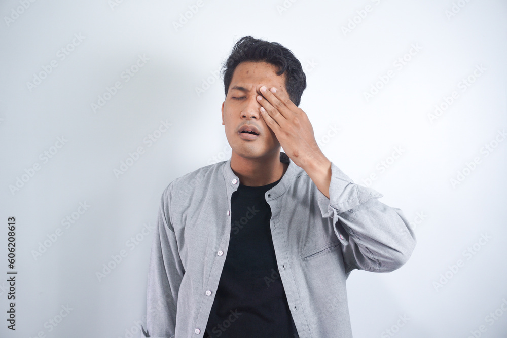 Tired Asian man covering one eye with palm as if having his eyes tested during vision examination trying to see letters. Eyesight problem concept Tired Asian man covering one eye with palm as if having his eyes tested during vision examination trying to see letters. Eyesight problem concept
