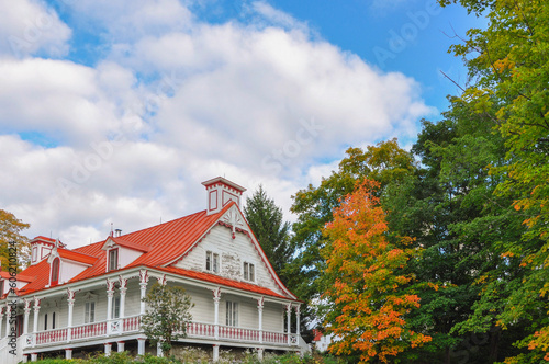 Traditional white and orange house on fall season with trees and blue sky change