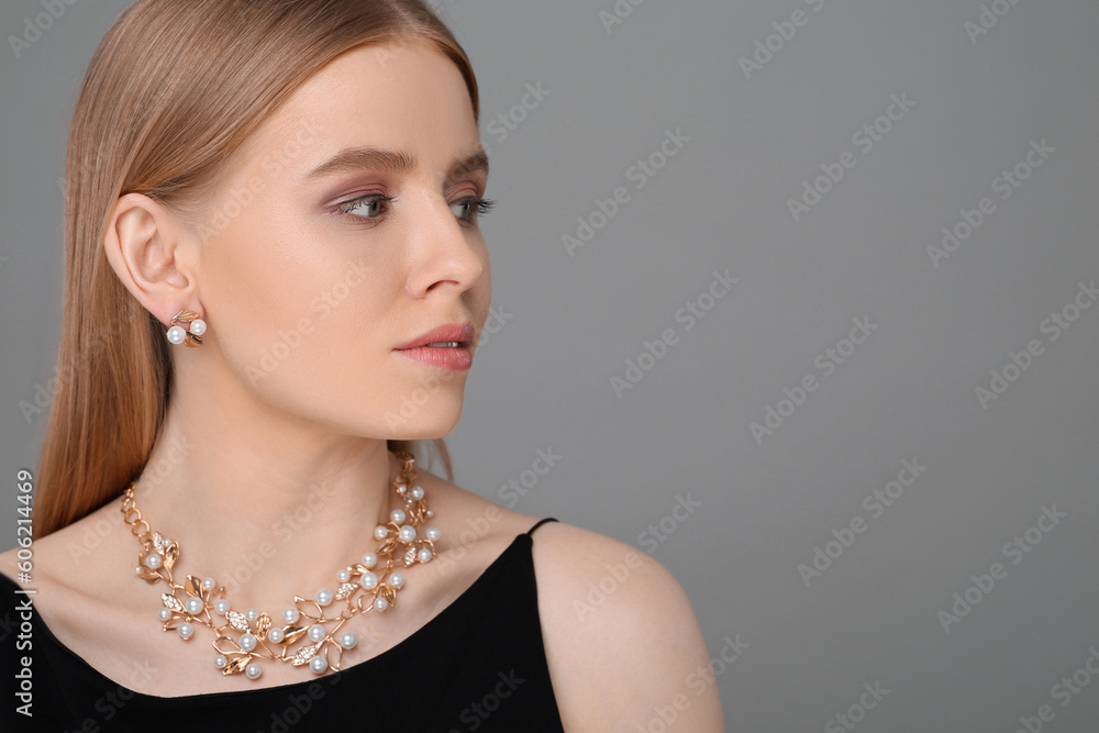Beautiful young woman with elegant jewelry on gray background, space for text Beautiful young woman with elegant jewelry on gray background, space for text