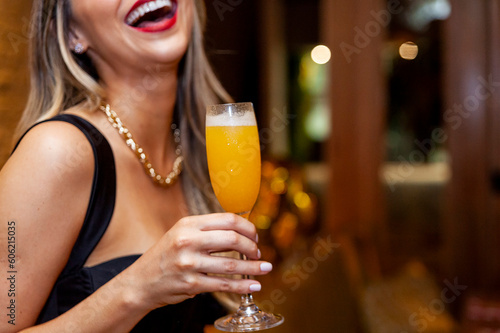 blonde woman holding mimosa glass and smiling