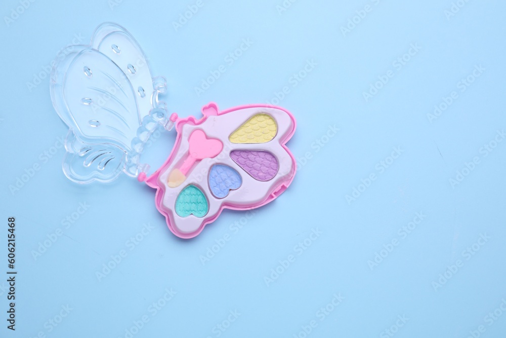 Decorative cosmetics for kids. Eye shadow palette on light blue background, top view. Space for text