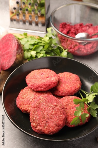 Delicious beetroot cutlets and parsley in black bowl on table. Vegan dish