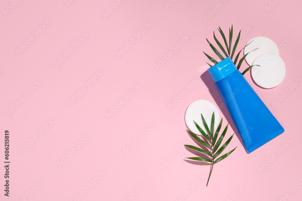 Tube of face cleansing product, leaves and cotton pads on pink background, flat lay. Space for text Tube of face cleansing product, leaves and cotton pads on pink background, flat lay. Space for text
