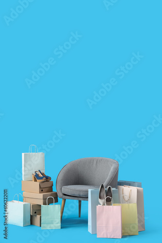 Shoe boxes with shopping bags and armchair on blue background © Pixel-Shot