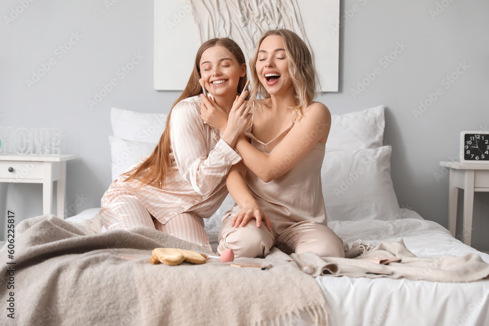 Young sisters with makeup brushes in bedroom Young sisters with makeup brushes in bedroom