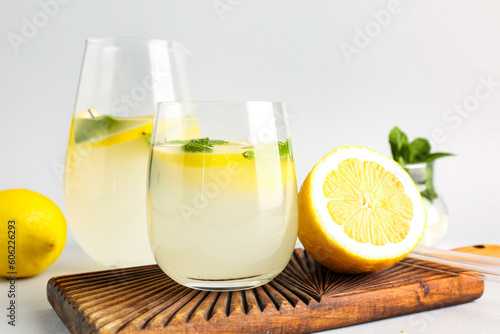 Board with glass and jug of fresh lemonade on grey background