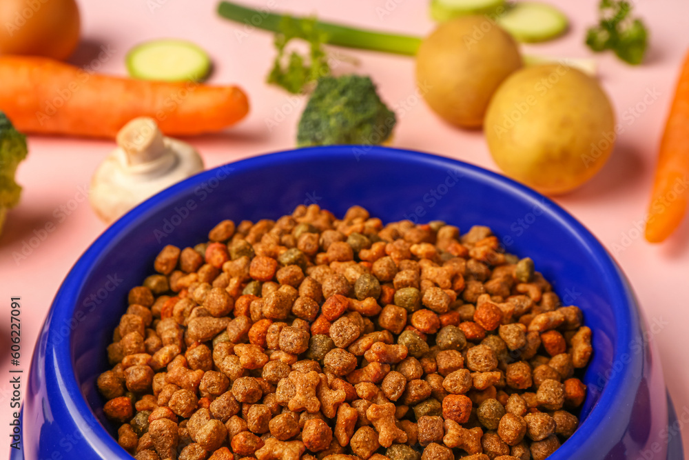 Bowl with dry pet food and natural products on pink background, closeup Bowl with dry pet food and natural products on pink background, closeup