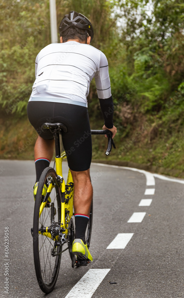 Naklejka premium Chasing the Summit: Cyclist Climbing a Mountain Road During a Competitive Race