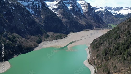 Blue lake surrounded by snow capped mountains. Switzerland. Aerial backward view photo