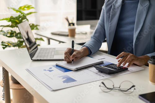 A businesswoman who works in a financial auditing office and allocates a company's budget in a desk office with statistical analysis, marketing graphs, remote images.
