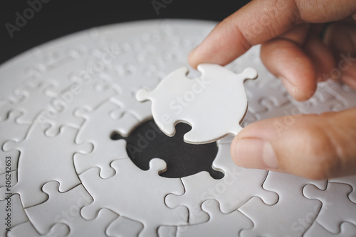 Hand put the last piece of jigsaw puzzle to complete the mission. Completing final task, missing jigsaw puzzle pieces and business concept with a puzzle piece missing.