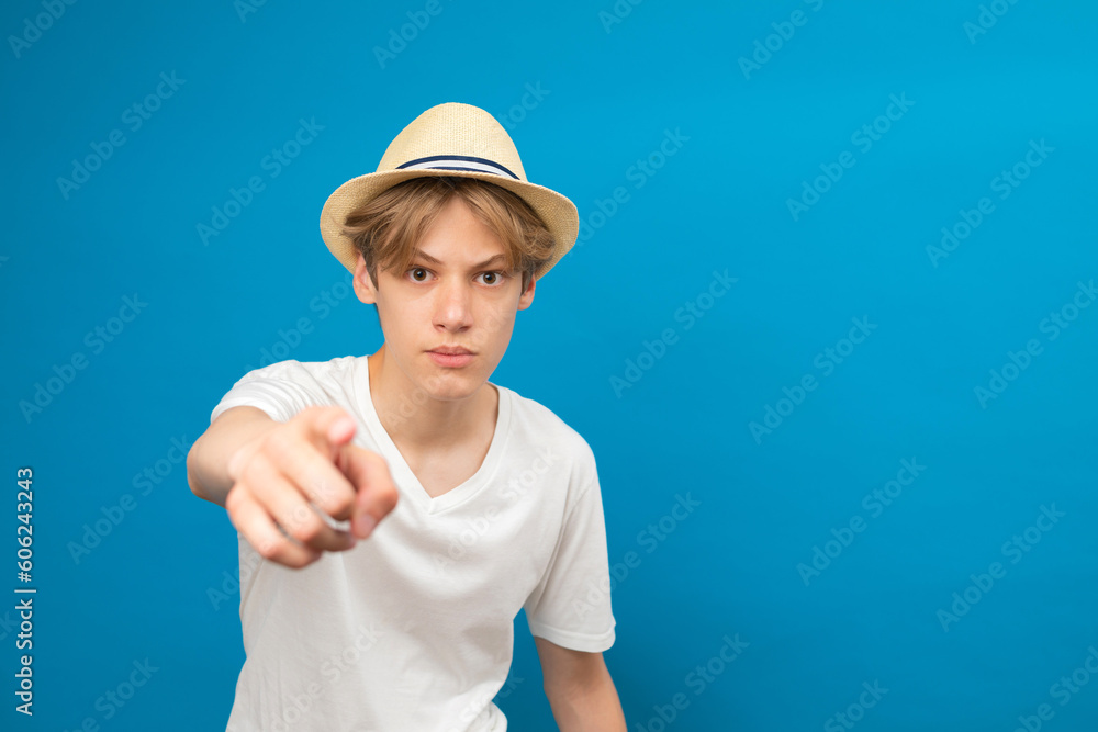 Teenager boy standing on blue isolated background pointing with finger to the camera and to you, hand sign, positive and confident gesture from the front Teenager boy standing on blue isolated background pointing with finger to the camera and to you, hand sign, positive and confident gesture from the front