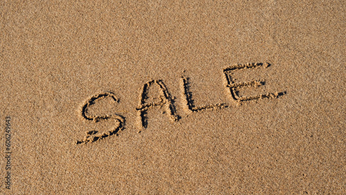 Text SALE handwritten in sand surface. Concept of promotion Black Friday Blue ocean wave washing away message at the beach. Summer holidays beach writing vacation concept © anna.stasiia