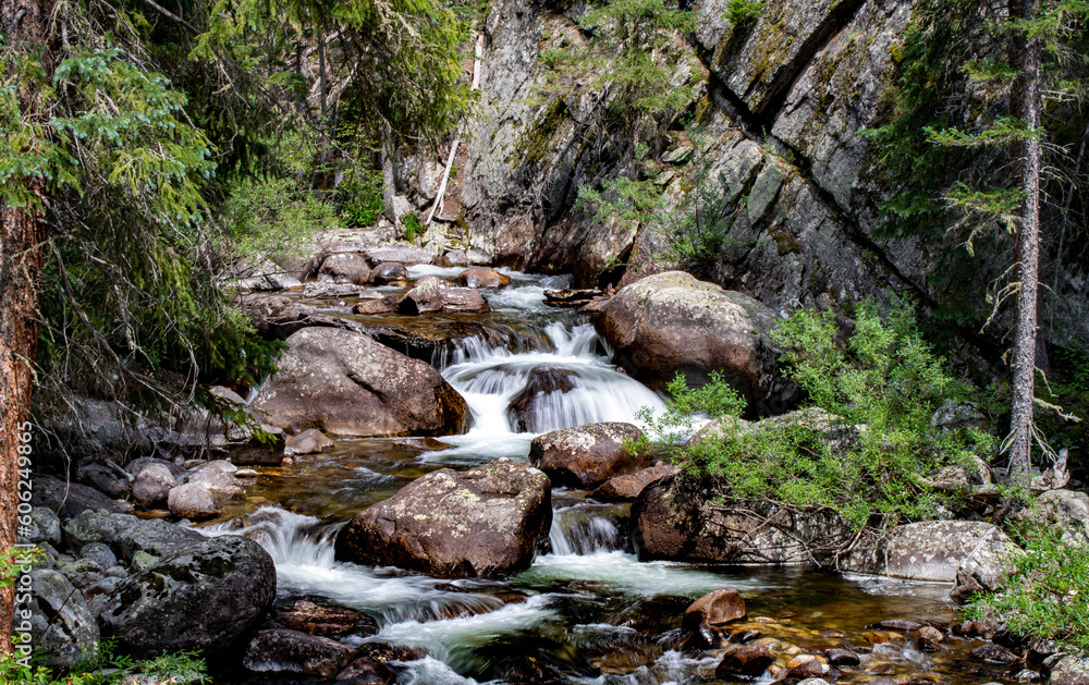 Waterfall in the Rocky Mountains Colorado on a beautiful summer day surrounded by green lush trees Waterfall in the Rocky Mountains Colorado on a beautiful summer day surrounded by green lush trees