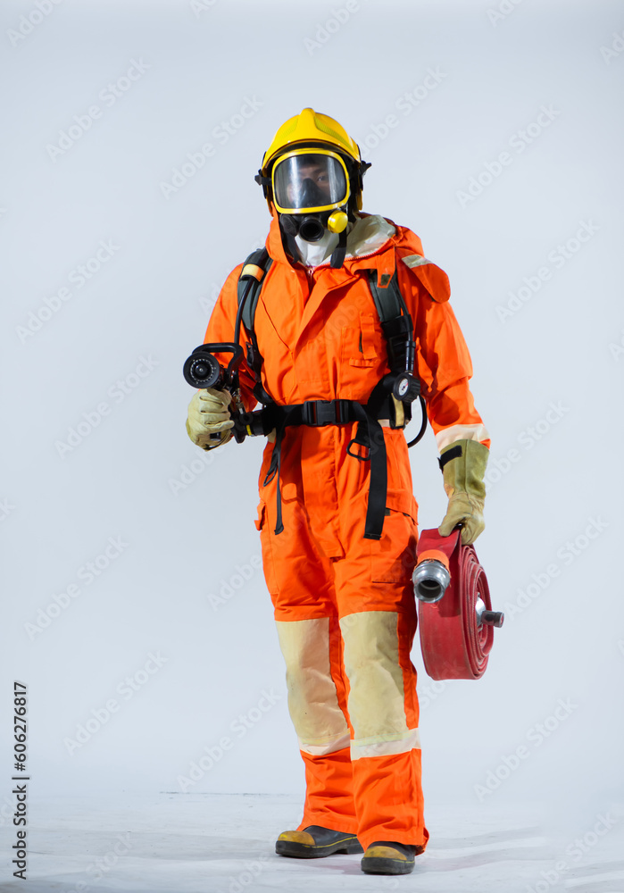 Professional firefighter wearing yellow helmet standing confidently on white background while holding a fire hose Professional firefighter wearing yellow helmet standing confidently on white background while holding a fire hose