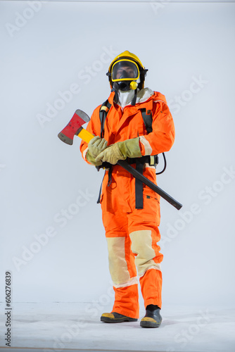 Professional firefighter is holding an iron axe with both hands and looking at the camera on a white background.