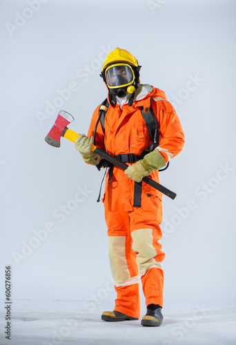Professional firefighter is holding an iron axe with both hands and closing his eyes on a white background.