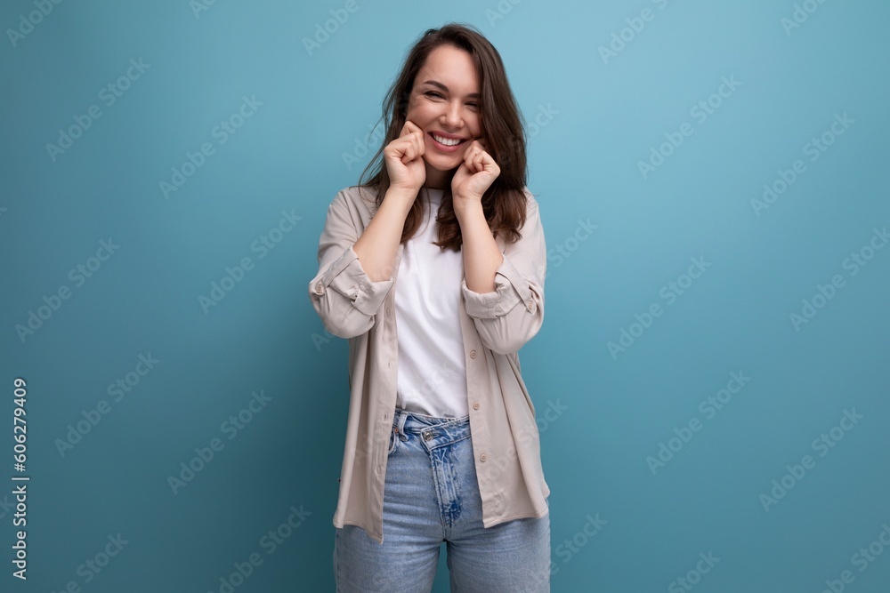 brunette young female adult in shirt and jeans smiling on background with copy space brunette young female adult in shirt and jeans smiling on background with copy space