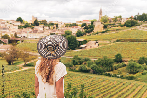 Leinwand Poster Rear view of woman looking at green vineyard in Bordeaux region, Saint Emilion-