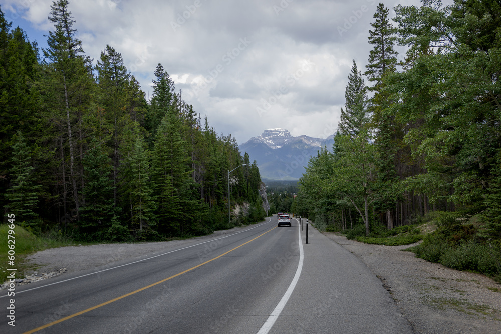 Windy road in Banff National Park, Banff, Alberta, Canada. cars parking. Mountain road with forest and cliffs. Windy road in Banff National Park, Banff, Alberta, Canada. cars parking. Mountain road with forest and cliffs.