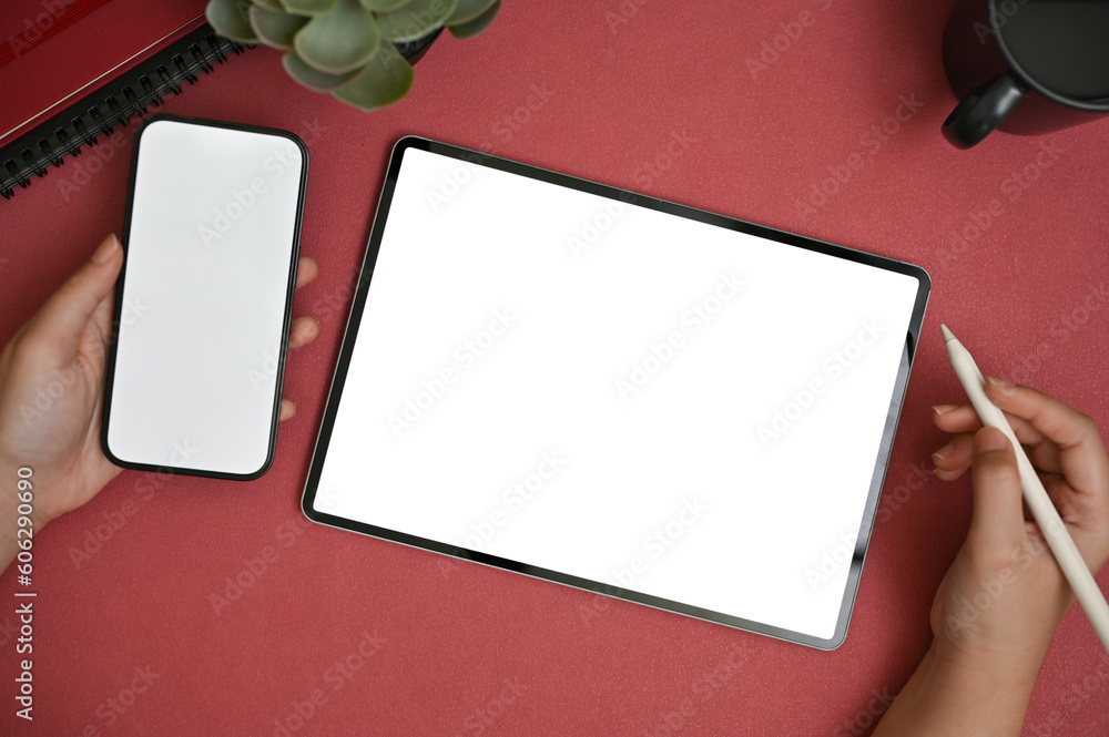 Obraz premium Top view of a female using her smartphone and her digital tablet on a red table.