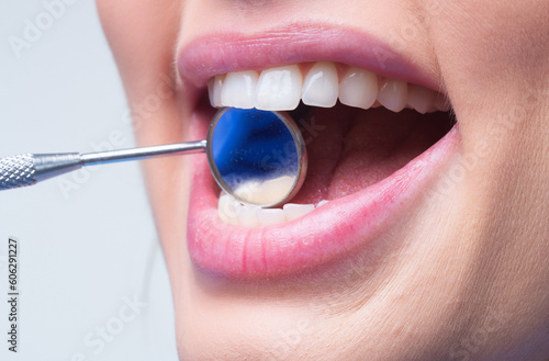 Teeth mirror close-up. Examination of teeth with dental mirror. Tooth filling. Teeth examined at dentist stomatology. White tooth and a dentist mouth mirror. Ideal teeth. Dental tools and stomatology. © Volodymyr