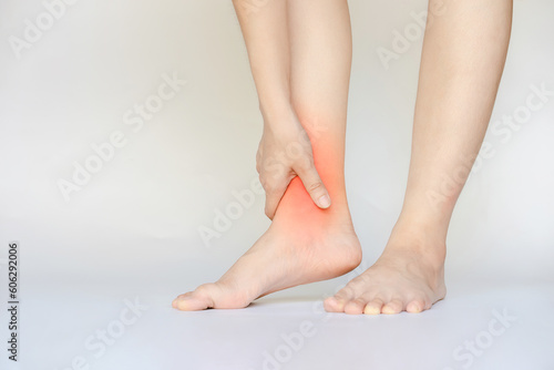 Fototapeta Naklejka Na Ścianę i Meble -  A woman's hand touches her red ankle due to an ankle injury caused by an accident.