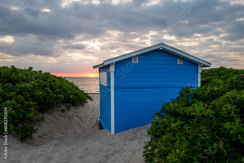 Tiny beach hut in the sand dunes. Sunset view from the beach in summer. Tisvildeleje, Denmark.