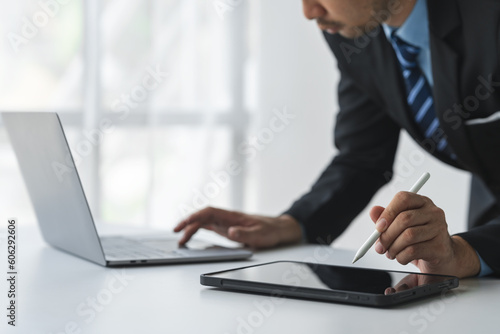 Businessman working on laptop in modern office Analyze business documents with financial graphs. market report on digital tablet business and marketing data analysis concept.